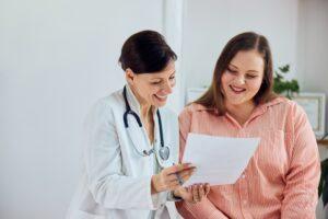 A weight loss clinic staff member speaks with a patient who is interested in learning how long semaglutide side effects last.