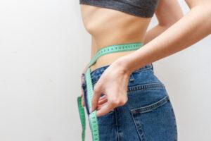 Woman is measuring waist after weight loss.